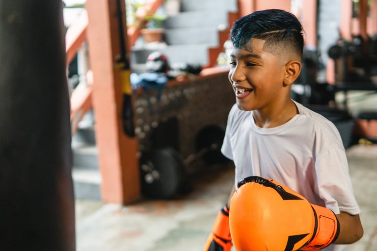 Happy boy practicing boxing, developing skills and confidence in a gym setting